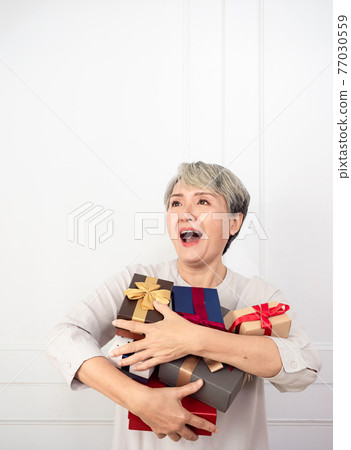 Senior asian woman holding mount of gift boxes, enjoying many best presents. 77030559