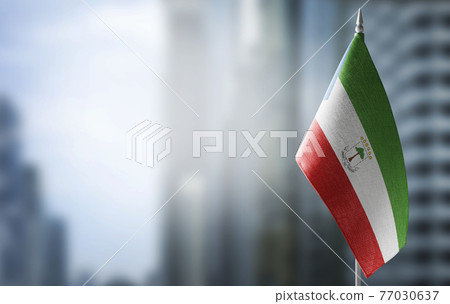 A small flag of Equatorial Guinea on the background of a blurred background 77030637