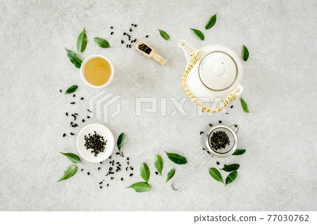 Herbal tea with two white tea cups and teapot, with green tea leaves. Flat lay, top view. Tea concept Herbal tea with two white tea cups and teapot, with green tea leaves. Flat lay, top view. Tea concept 77030762