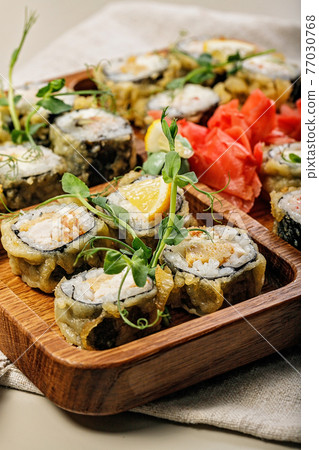 Close-up assorted hot rolls with eel, Japanese omelet, cream cheese, fried onions and unagi sauce with fresh herbs. Japanese food on a bamboo platter. Vertical shot Close-up assorted hot rolls with eel, Japanese omelet, cream cheese, fried onions and unagi sauce with fresh herbs. Japanese food on a bamboo platter. Vertical shot 77030768