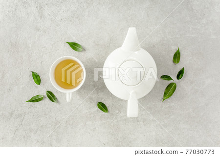 Herbal tea with two white tea cups and teapot, with green tea leaves. Flat lay, top view. Tea concept 77030773