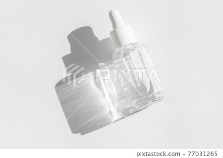 Transparent liquid product packaging in glass bottle. Anti aging serum with collagen and peptides on white with sunlight and shadow. Hyaluronic or polyglutamic acid oil cosmetic mockup. Transparent liquid product packaging in glass bottle. Anti aging serum with collagen and peptides on white with sunlight and shadow. Hyaluronic or polyglutamic acid oil cosmetic mockup. 77031265