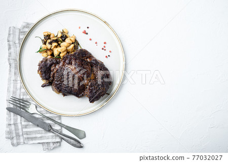 Cooked rib-eye steak with white beans, on white stone surface, top view flat lay, with copy space for text Cooked rib-eye steak with white beans, on white stone surface, top view flat lay, with copy space for text 77032027