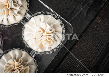 Manti, Turkish traditional ravioli, in plastic tray, on black wooden table background, top view flat lay, with copy space for text 77032056