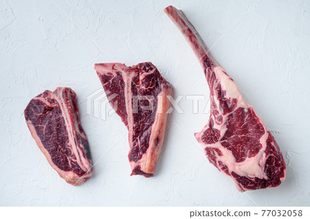 Dry aged marbled beef meat cut, tomahawk, t bone or porterhouse and club steak, on white stone background, top view flat lay 77032058