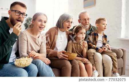 Happy big family watching TV and eating popcorn Happy big family watching TV and eating popcorn 77032075