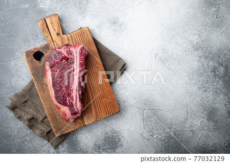 Club raw steak with herbs and salt prepared for cooking, on gray stone background, top view flat lay, with copy space for text 77032129