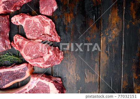 Raw beef meat steaks, tomahawk, t bone, club steak, rib eye and tenderloin cuts, on old dark wooden table background, top view flat lay, with copy space for text Raw beef meat steaks, tomahawk, t bone, club steak, rib eye and tenderloin cuts, on old dark wooden table background, top view flat lay, with copy space for text 77032151