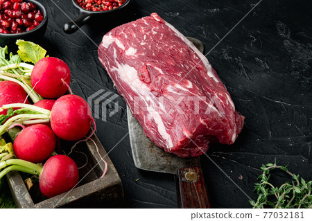 Raw beef fillet steaks with spices and whole marbled tenderloin cut, on old butcher cleaver knife, on black stone background, with copy space for text Raw beef fillet steaks with spices and whole marbled tenderloin cut, on old butcher cleaver knife, on black stone background, with copy space for text 77032181