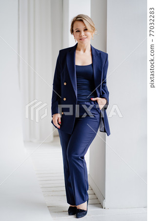 blonde woman in a blue suit poses standing in a photo studio. businesswoman blonde woman in a blue suit poses standing in a photo studio. businesswoman 77032283