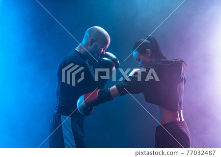 Woman exercising with trainer at boxing and self defense lesson Woman exercising with trainer at boxing and self defense lesson 77032487