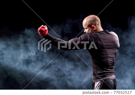 Sportsman boxer fighting on black background with smoke. Boxing Sportsman boxer fighting on black background with smoke. Boxing 77032527