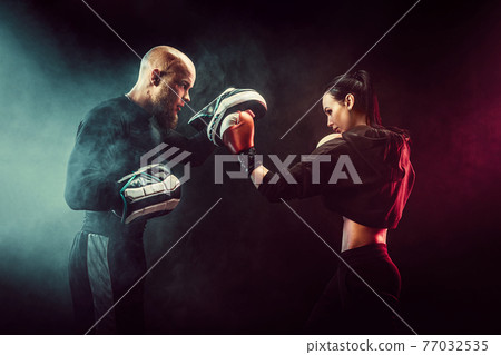 Woman exercising with trainer at boxing and self defense lesson Woman exercising with trainer at boxing and self defense lesson 77032535