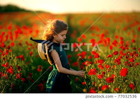 Girl in dress and straw hat outdoor At Poppy Field 77032536