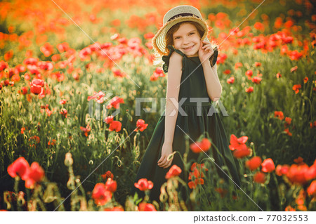 Girl in dress and straw hat outdoor At Poppy Field 77032553