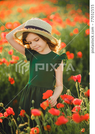 Girl in dress and straw hat outdoor At Poppy Field 77032555