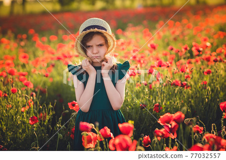 Girl in dress and straw hat outdoor At Poppy Field 77032557