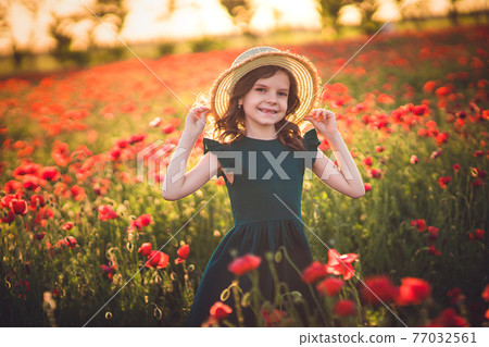 Girl in dress and straw hat outdoor At Poppy Field 77032561