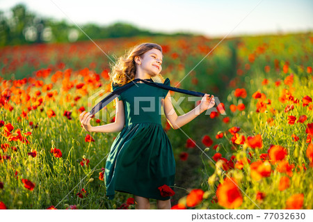 Girl in dress and straw hat outdoor At Poppy Field 77032630