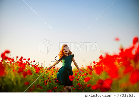 Girl in dress and straw hat outdoor At Poppy Field 77032633