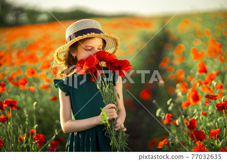 Girl in dress and straw hat outdoor At Poppy Field 77032635