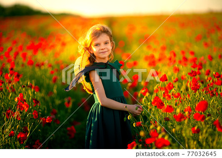 Girl in dress and straw hat outdoor At Poppy Field 77032645