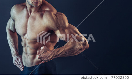 Unrecognizable Strong Athletic Sexy Muscular Man Poising , Showing biceps and delts on Black Background Unrecognizable Strong Athletic Sexy Muscular Man Poising , Showing biceps and delts on Black Background 77032800