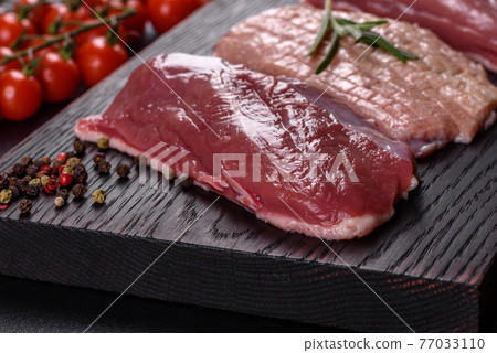 Raw duck breast with herbs and spices on a dark concrete background Raw duck breast with herbs and spices on a dark concrete background 77033110