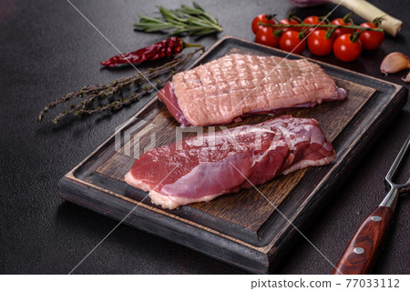Raw duck breast with herbs and spices on a dark concrete background Raw duck breast with herbs and spices on a dark concrete background 77033112