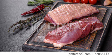 Raw duck breast with herbs and spices on a dark concrete background Raw duck breast with herbs and spices on a dark concrete background 77033113