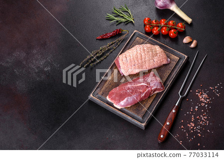 Raw duck breast with herbs and spices on a dark concrete background Raw duck breast with herbs and spices on a dark concrete background 77033114