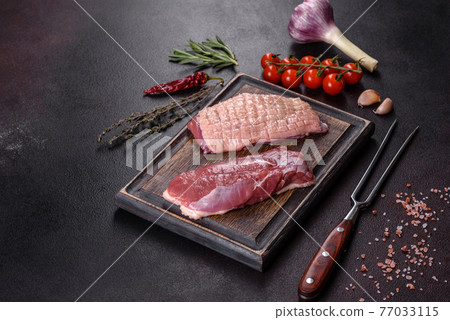 Raw duck breast with herbs and spices on a dark concrete background Raw duck breast with herbs and spices on a dark concrete background 77033115