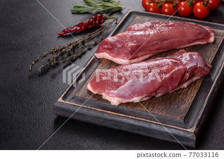 Raw duck breast with herbs and spices on a dark concrete background Raw duck breast with herbs and spices on a dark concrete background 77033116