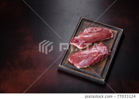 Raw duck breast with herbs and spices on a dark concrete background Raw duck breast with herbs and spices on a dark concrete background 77033124