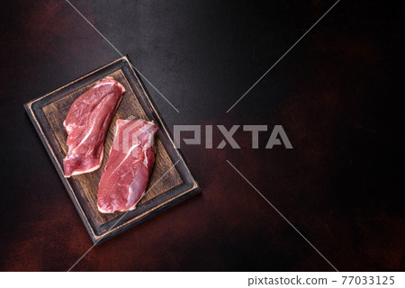Raw duck breast with herbs and spices on a dark concrete background Raw duck breast with herbs and spices on a dark concrete background 77033125