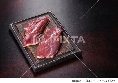 Raw duck breast with herbs and spices on a dark concrete background Raw duck breast with herbs and spices on a dark concrete background 77033126