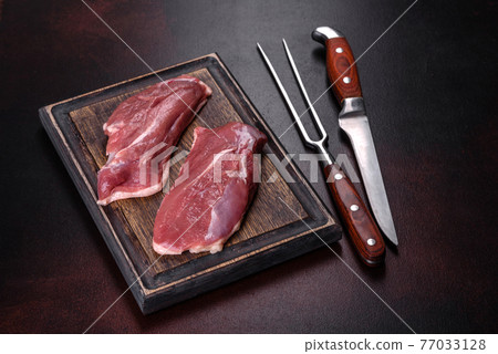 Raw duck breast with herbs and spices on a dark concrete background Raw duck breast with herbs and spices on a dark concrete background 77033128
