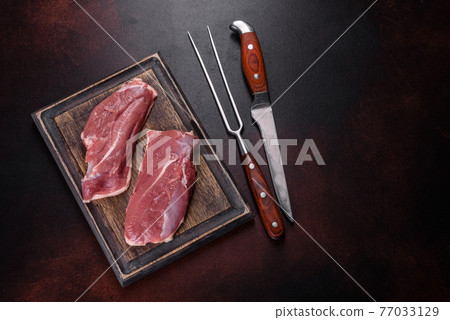 Raw duck breast with herbs and spices on a dark concrete background Raw duck breast with herbs and spices on a dark concrete background 77033129