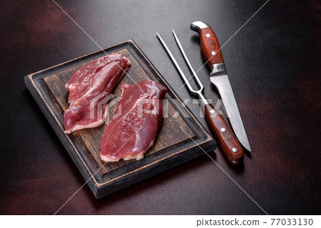 Raw duck breast with herbs and spices on a dark concrete background Raw duck breast with herbs and spices on a dark concrete background 77033130
