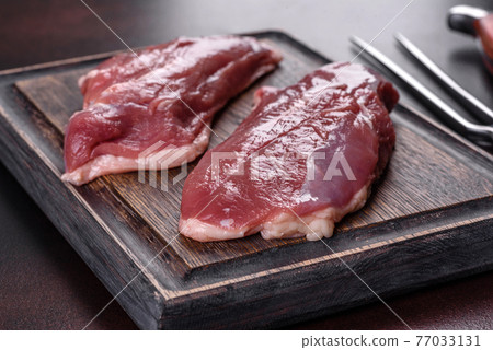 Raw duck breast with herbs and spices on a dark concrete background Raw duck breast with herbs and spices on a dark concrete background 77033131