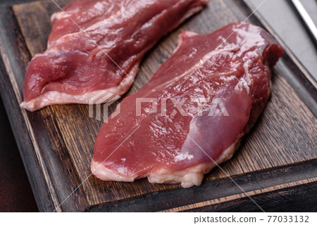 Raw duck breast with herbs and spices on a dark concrete background Raw duck breast with herbs and spices on a dark concrete background 77033132