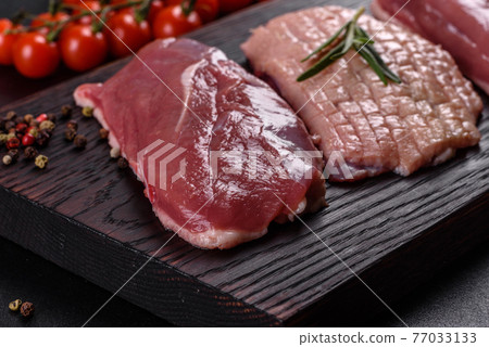 Raw duck breast with herbs and spices on a dark concrete background Raw duck breast with herbs and spices on a dark concrete background 77033133