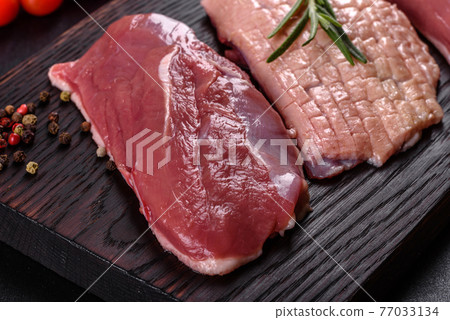 Raw duck breast with herbs and spices on a dark concrete background Raw duck breast with herbs and spices on a dark concrete background 77033134