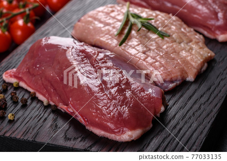Raw duck breast with herbs and spices on a dark concrete background Raw duck breast with herbs and spices on a dark concrete background 77033135