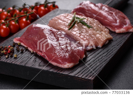 Raw duck breast with herbs and spices on a dark concrete background 77033136