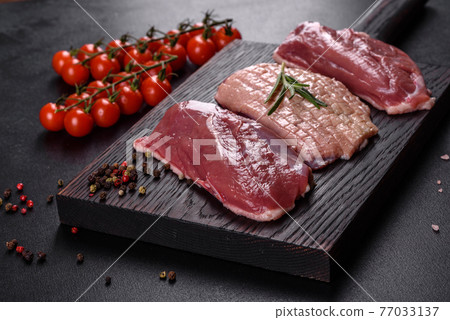 Raw duck breast with herbs and spices on a dark concrete background Raw duck breast with herbs and spices on a dark concrete background 77033137