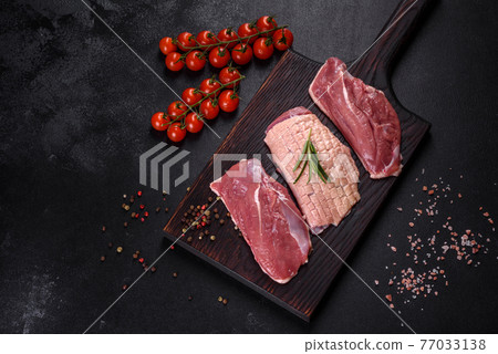 Raw duck breast with herbs and spices on a dark concrete background Raw duck breast with herbs and spices on a dark concrete background 77033138