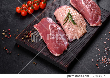 Raw duck breast with herbs and spices on a dark concrete background Raw duck breast with herbs and spices on a dark concrete background 77033140