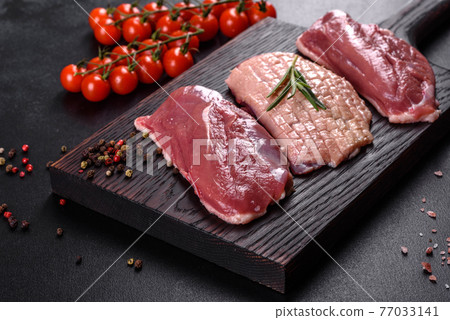 Raw duck breast with herbs and spices on a dark concrete background Raw duck breast with herbs and spices on a dark concrete background 77033141