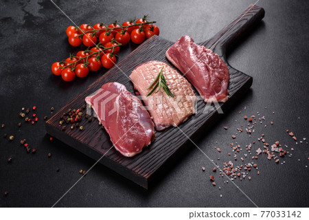 Raw duck breast with herbs and spices on a dark concrete background Raw duck breast with herbs and spices on a dark concrete background 77033142